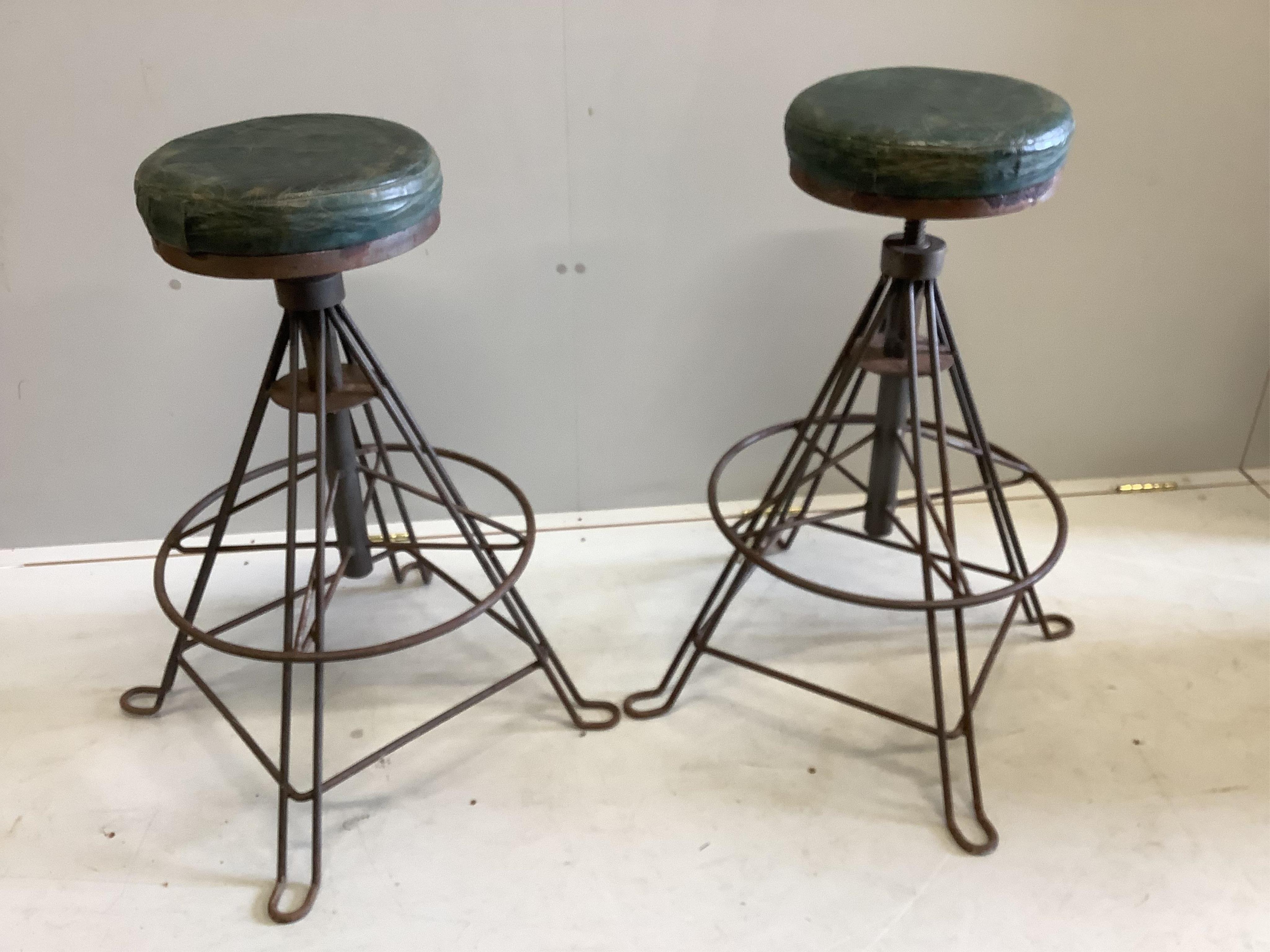 A pair of industrial style wrought iron adjustable stools